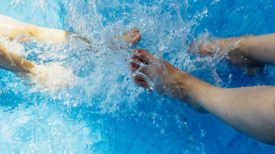 zwei planschende Fußpaare in einem Pool