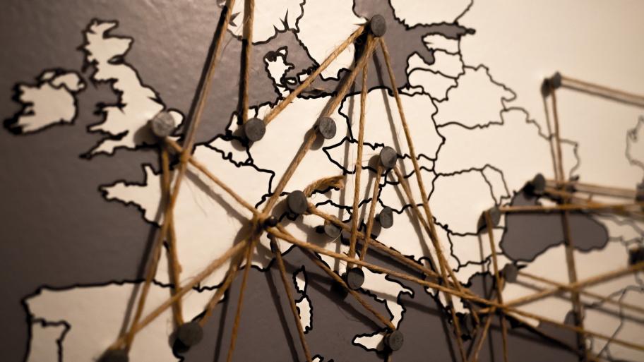 Weltkarte an einer Wand, Verbindungen zwischen einzelnen Punkten mit Fäden gespannt