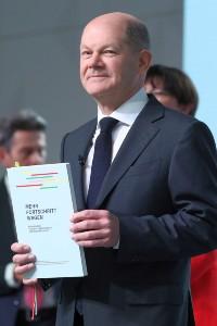 Bundeskanzler Olaf Scholz hält den unterschriebenen Koalitionsvertrag von SPD, FDP und Grünen in der Hand, er trägt Anzug und Krawatte