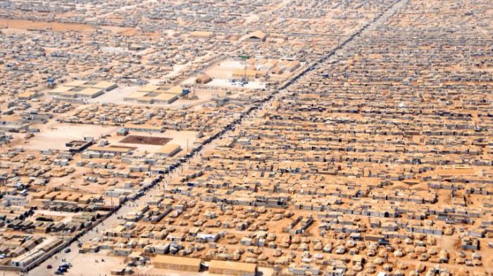 Luftaufnahme des Flüchtlingscamps Za’atari in Jordanien: eine riesige Ansammlung von kleinen Zelten und größeren Baracken bis zum Horizont, rechtwinklig angeordnet, Zelte und Boden sandfarben