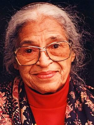 Porträt der Bürgerrechtlerin Rosa Parks, sie hat graue Haare; sie trägt eine Brille und einen roten Pullover, darüber ein buntes Tuch