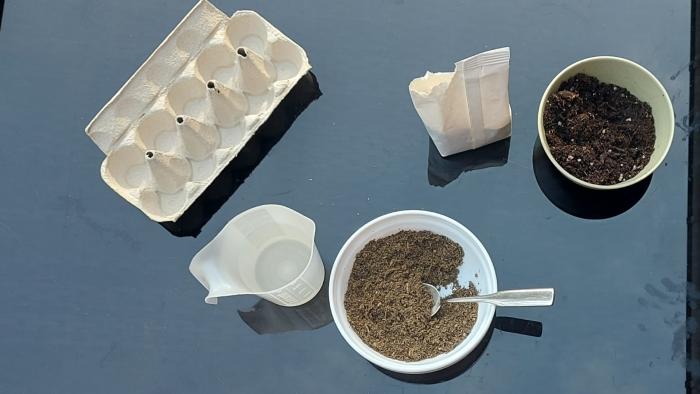 Schüssel mit Erdenmix und Messbecher mit Wasser