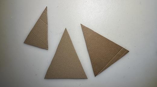 Drei Papp-Dreiecke auf weißer Unterlage
