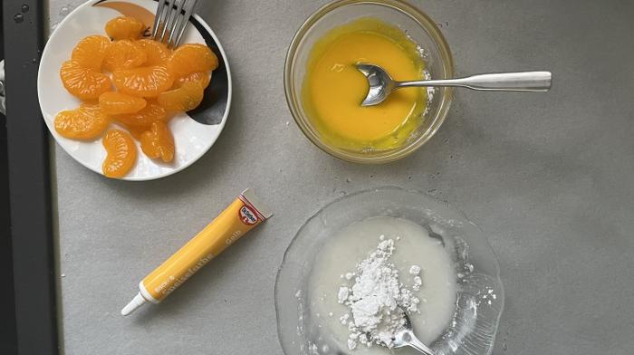 Mandarinenscheiben, gelbe Lebensmittelfarbe mit Puderzucker in einer Schüssel und nur Puderzucker mit Zitronensaft