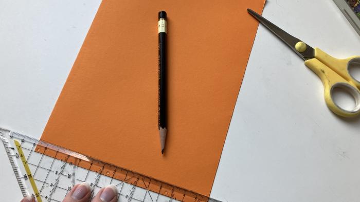 Auf das gefaltete Papier wird ein Rand gezeichnet, der abgeschnitten wird.