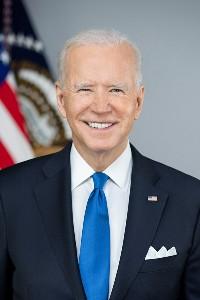 Porträt des amerikanischen Präsidenten Joe Biden, er trägt Anzug und Krawatte, im Hintergrund die amerikanische Flagge