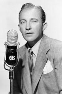 Schwarz-Weiß-Porträt des Musikes Bing Crosby von 1951, er schaut in die Kamera, trägt Anzug und Krawatte und steht vor einem Mikrofon
