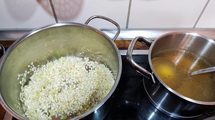 Im linken Topf ist Reis mit Zwiebel und im rechten Topf Brühe