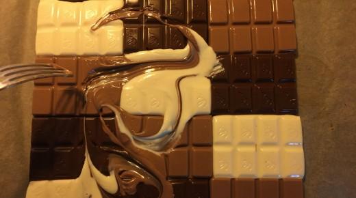 Flüssige Schokolade wird mit einer Gabel ineinander gemischt; ein schönes Muster ensteht