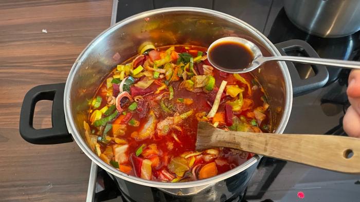 Suppe in einem Topf, die gewürzt wird.