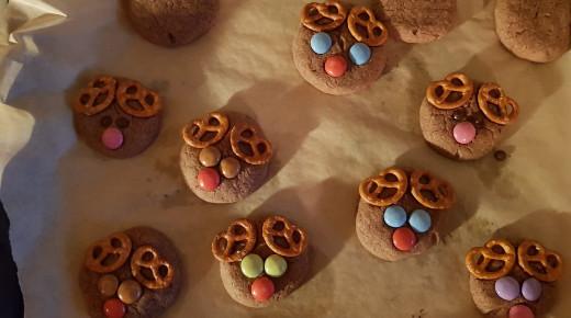 Schritt 4; die gebackenen Kekse werden wurden mit Salzbrezeln und bunten Smarties verziert, sodass sie aussehen wie kleine Rentier-Köpfe