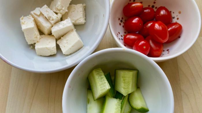 Zu sehen sind drei Schüsseln mit den verschiedenen Zutaten: Fetakäse, Gurke und Tomate.