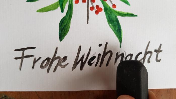 fertig gemaltes Motiv: ein Ast mit grünen Blättern und roten Beeren; "Frohe Weihnacht" steht unten drunter; in der rechten Ecke ist ein schwarzer Radiergummi