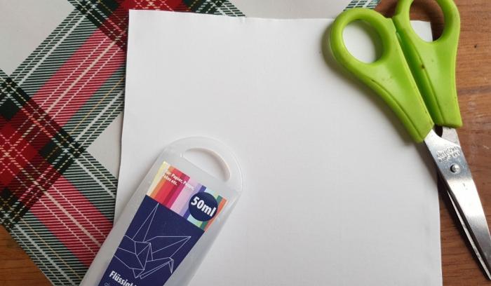weißes Blatt Papier, rechte obere Ecke ist eine grüne Schere, linke untere Ecke bunte Stifte