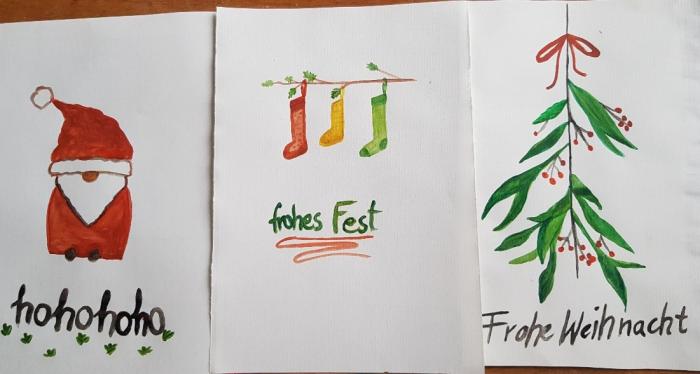 drei Wiehnachtkarten: linke mit Weihnachtsmannmotiv, mitte mit hängenden Socken, rechts ein Strauch